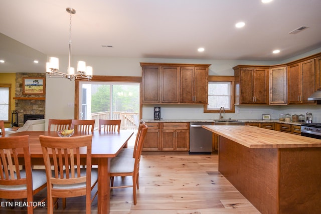 kitchen with visible vents, a sink, under cabinet range hood, stainless steel dishwasher, and butcher block counters