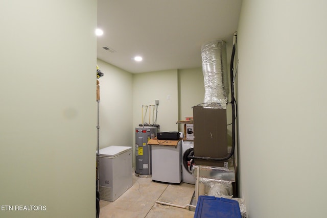 clothes washing area featuring water heater, visible vents, washer / clothes dryer, and laundry area