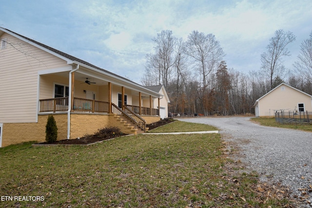 view of property exterior with gravel driveway, a porch, a ceiling fan, and a lawn