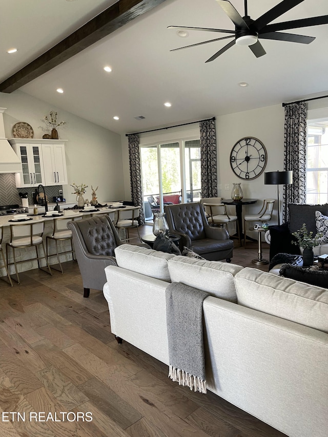 living area featuring dark wood finished floors, a healthy amount of sunlight, lofted ceiling with beams, and ceiling fan