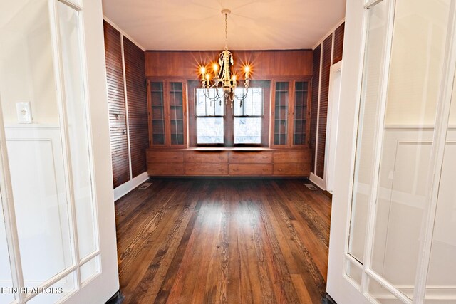 717 N Charles Seivers Blvd, Clinton, TN 37716 - unfurnished dining area with baseboards, dark wood-style flooring, wooden walls, and an inviting chandelier