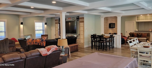 living room featuring decorative columns, coffered ceiling, and wood finished floors