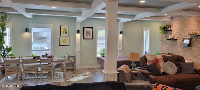 living area featuring wood finished floors, baseboards, coffered ceiling, beam ceiling, and decorative columns