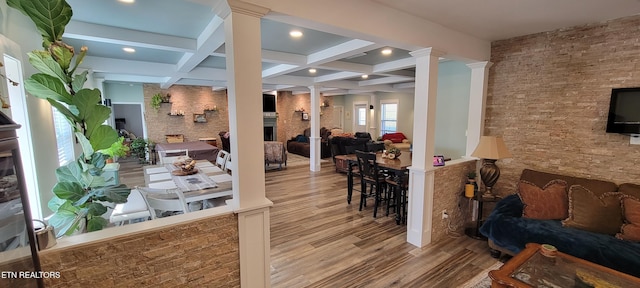 interior space with decorative columns, coffered ceiling, wood finished floors, and a fireplace