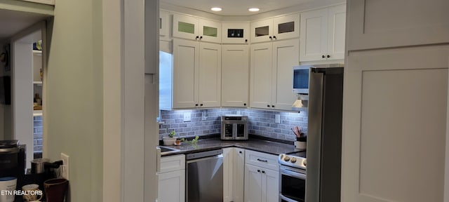 kitchen with recessed lighting, stainless steel appliances, white cabinetry, dark countertops, and tasteful backsplash