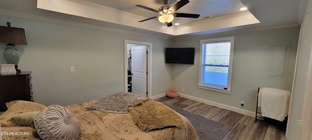 bedroom featuring visible vents, wood finished floors, a tray ceiling, and ornamental molding