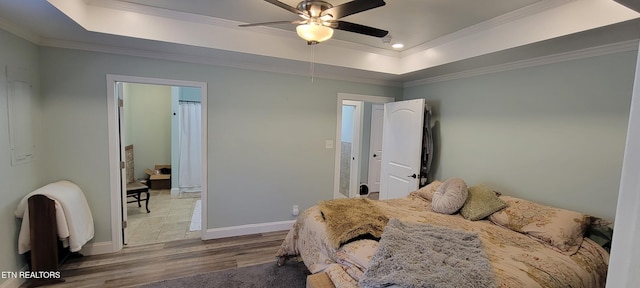 bedroom featuring baseboards, ornamental molding, wood finished floors, a raised ceiling, and a ceiling fan