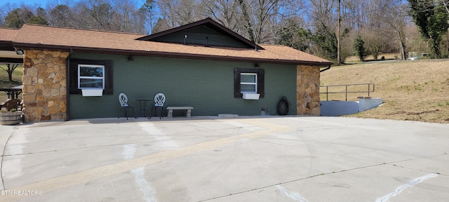 view of side of property featuring brick siding and stone siding