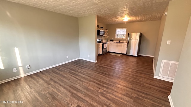 unfurnished room with visible vents, dark wood-style flooring, baseboards, and a sink