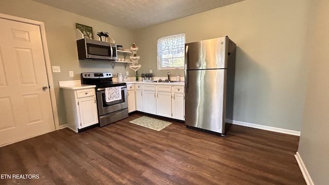 kitchen with dark wood finished floors, open shelves, light countertops, white cabinets, and appliances with stainless steel finishes