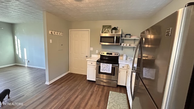 kitchen with dark wood-type flooring, appliances with stainless steel finishes, white cabinets, light countertops, and baseboards