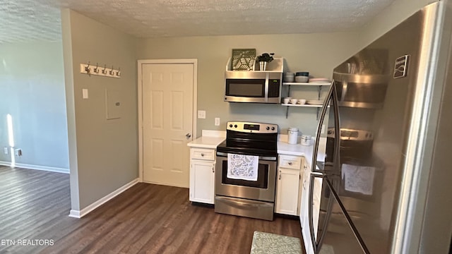 kitchen featuring a textured ceiling, dark wood-style floors, white cabinetry, stainless steel appliances, and light countertops