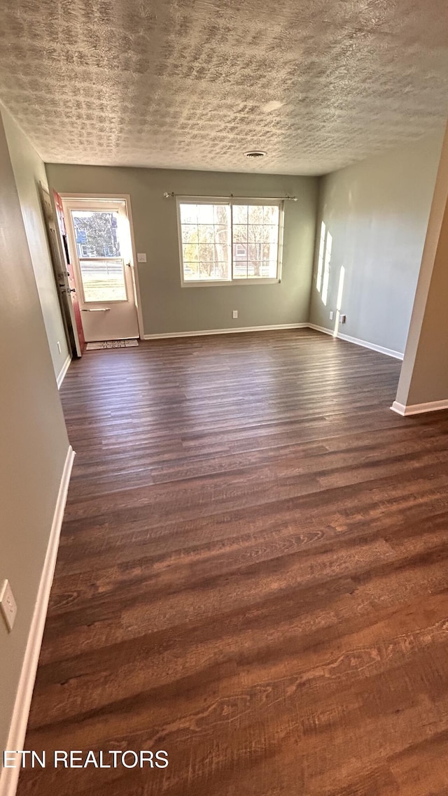 unfurnished living room featuring dark wood-style floors, baseboards, and a textured ceiling