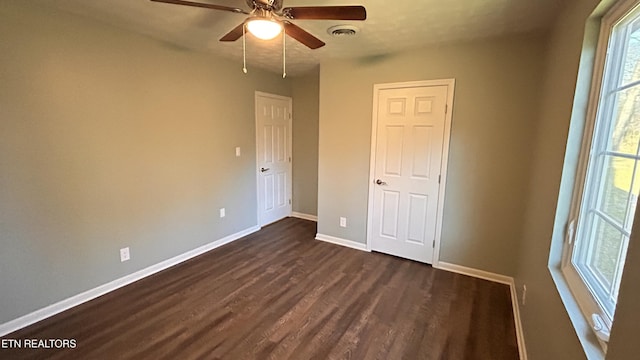 unfurnished bedroom with dark wood-style floors, baseboards, visible vents, and ceiling fan