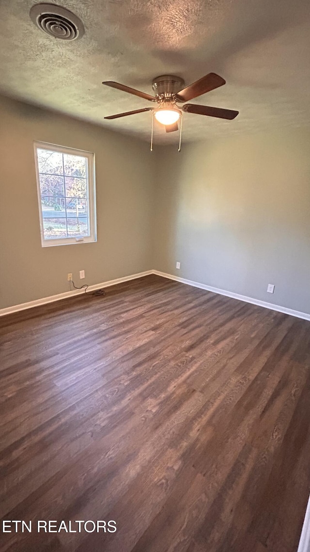 spare room with dark wood finished floors, visible vents, and a textured ceiling