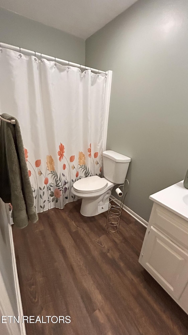 full bathroom with curtained shower, baseboards, toilet, wood finished floors, and vanity