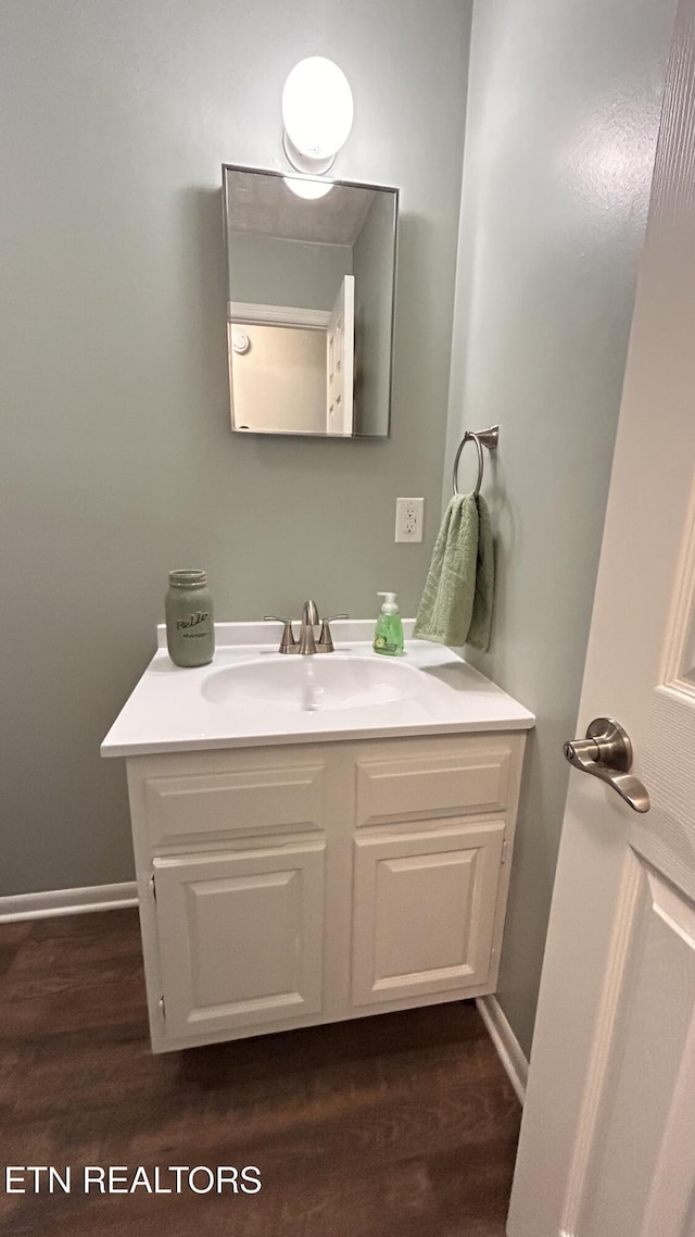 bathroom featuring vanity, baseboards, and wood finished floors