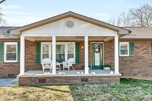 exterior space with a shingled roof, brick siding, covered porch, and crawl space