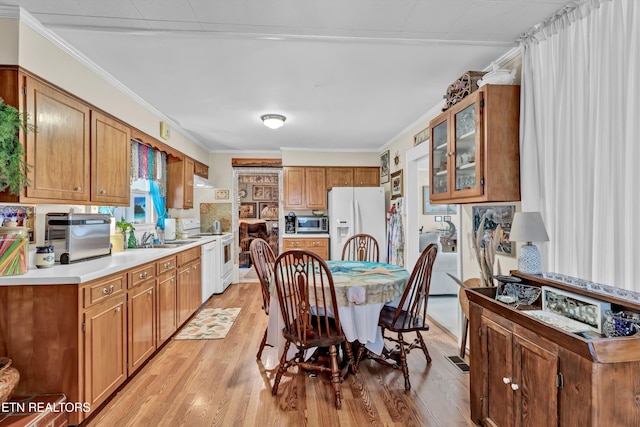 kitchen featuring light wood-style flooring, ornamental molding, white appliances, light countertops, and glass insert cabinets