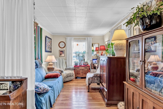 living area with light wood-type flooring and ornamental molding