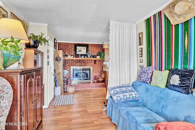 living area with crown molding, a brick fireplace, wood finished floors, and brick wall