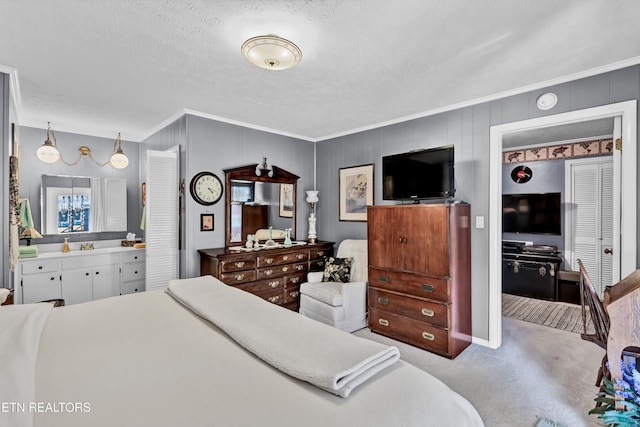 bedroom featuring ensuite bath, crown molding, carpet floors, and a textured ceiling