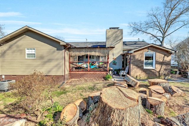 back of house with a deck, central air condition unit, brick siding, and a chimney