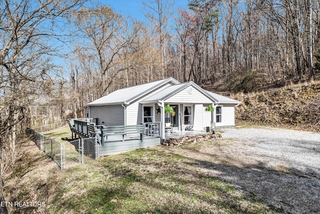 view of front of property featuring a gate, fence, a porch, a front lawn, and metal roof