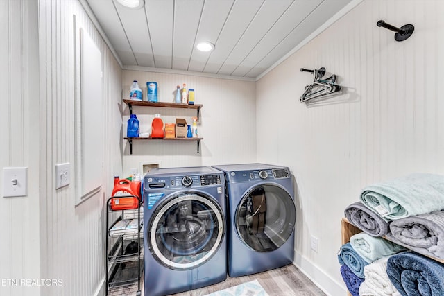 clothes washing area with laundry area, ornamental molding, wood finished floors, and washing machine and clothes dryer