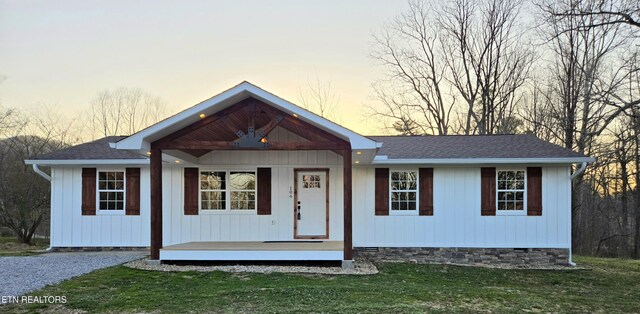 view of front of house with crawl space, a lawn, a porch, and a shingled roof