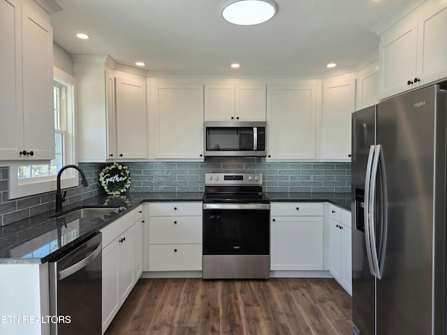 kitchen featuring a sink, decorative backsplash, dark wood-type flooring, appliances with stainless steel finishes, and white cabinetry