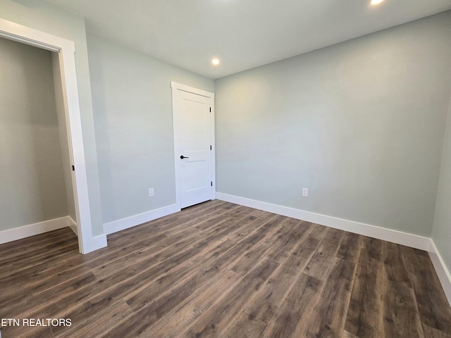 unfurnished room with recessed lighting, dark wood-style floors, and baseboards