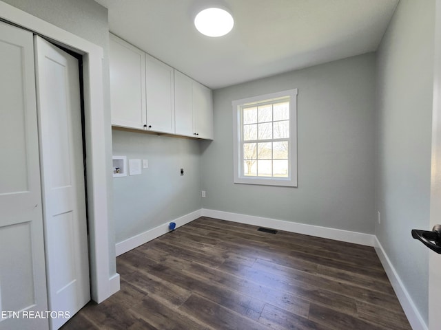 clothes washing area with cabinet space, electric dryer hookup, baseboards, and dark wood-style flooring