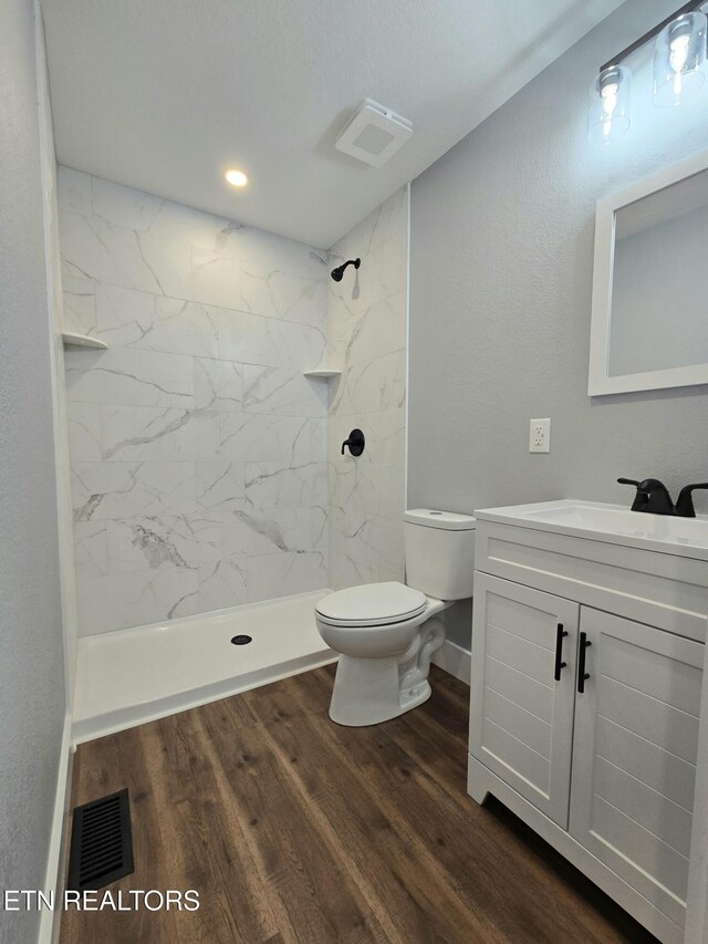 bathroom featuring visible vents, a shower stall, toilet, wood finished floors, and vanity