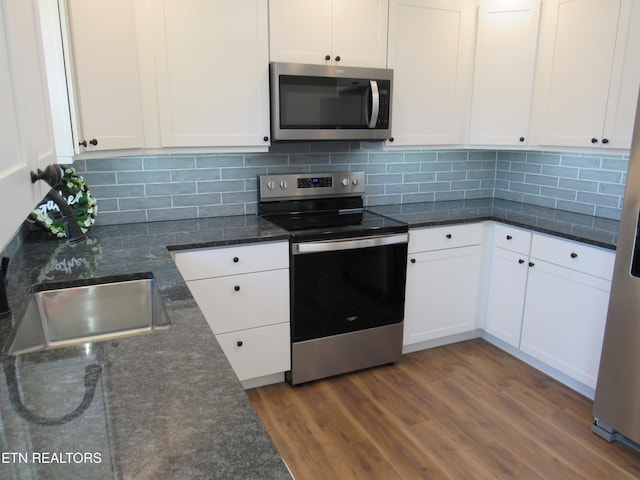 kitchen with a sink, stainless steel appliances, white cabinets, and dark wood-style flooring