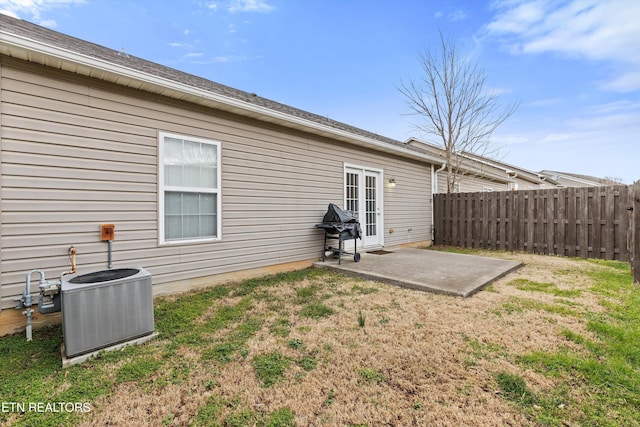 rear view of property featuring a patio, a yard, fence, and central AC