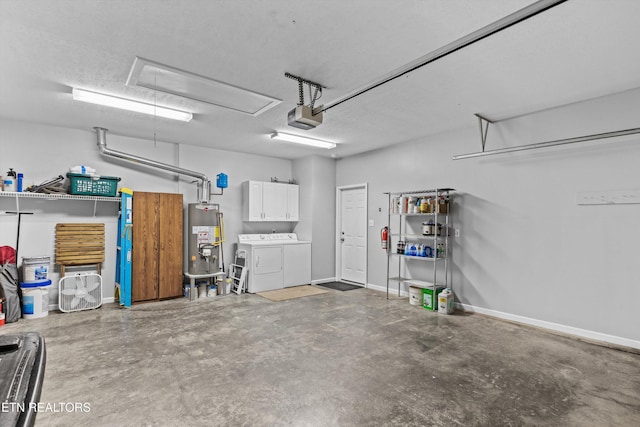 garage featuring baseboards, a garage door opener, water heater, and washer and clothes dryer