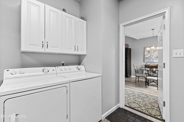 laundry room with baseboards, independent washer and dryer, cabinet space, and an inviting chandelier