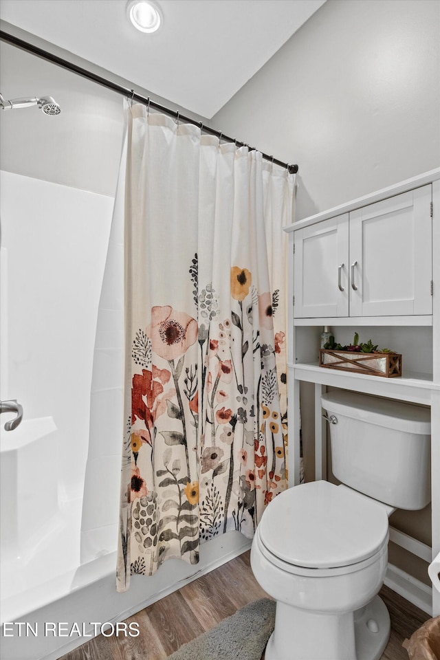 bathroom with toilet, shower / bath combo with shower curtain, and wood finished floors