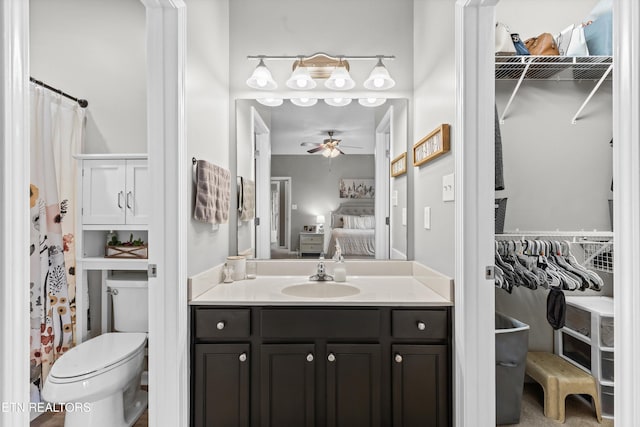 ensuite bathroom featuring vanity, ceiling fan, a spacious closet, toilet, and connected bathroom