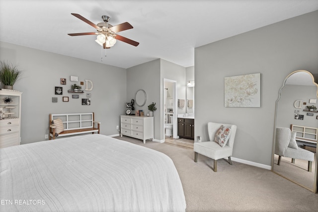 bedroom featuring light carpet, connected bathroom, a ceiling fan, and baseboards