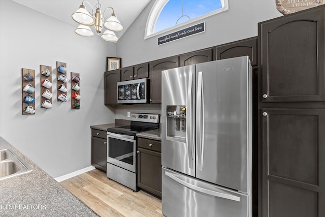 kitchen with dark brown cabinetry, light wood-type flooring, vaulted ceiling, appliances with stainless steel finishes, and a notable chandelier