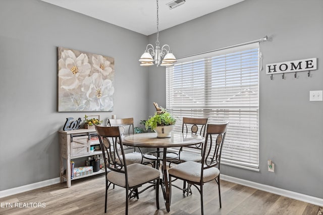 dining area with visible vents, a notable chandelier, wood finished floors, and baseboards