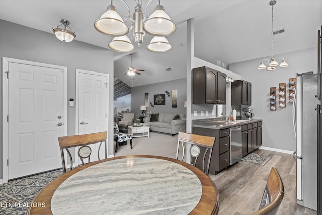 dining room featuring baseboards, visible vents, lofted ceiling, ceiling fan with notable chandelier, and light wood-type flooring