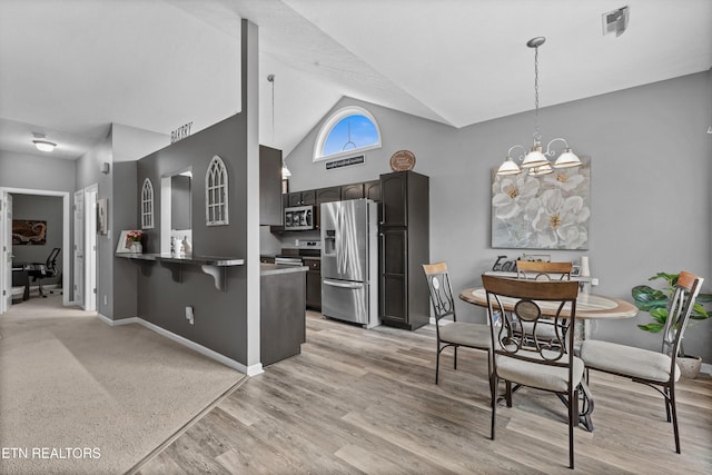 kitchen with a chandelier, pendant lighting, a peninsula, light wood-style floors, and stainless steel appliances