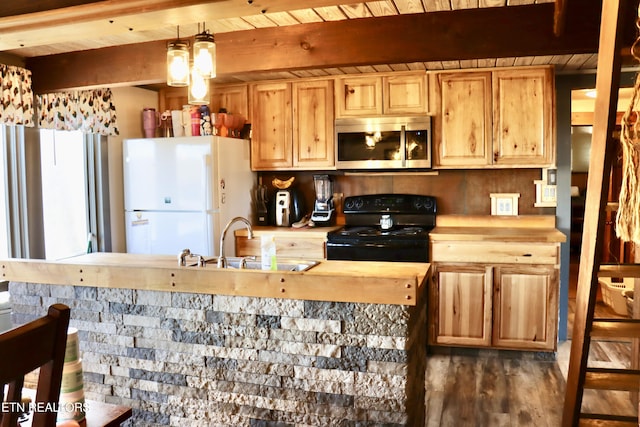 kitchen with black gas stove, freestanding refrigerator, a sink, wood counters, and stainless steel microwave