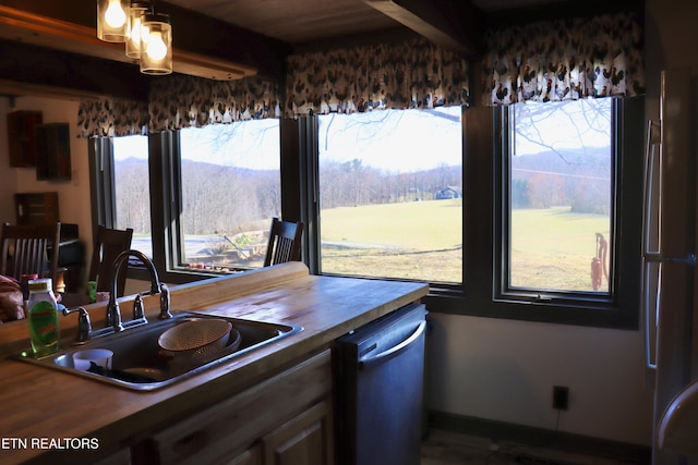 kitchen with beam ceiling, a sink, wood counters, dishwasher, and stainless steel fridge