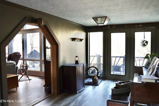 interior space featuring a textured ceiling, wood finished floors, and ornamental molding