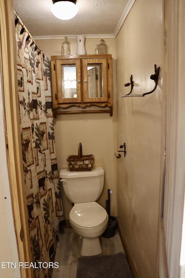 full bathroom featuring wood finished floors, a textured ceiling, toilet, and ornamental molding