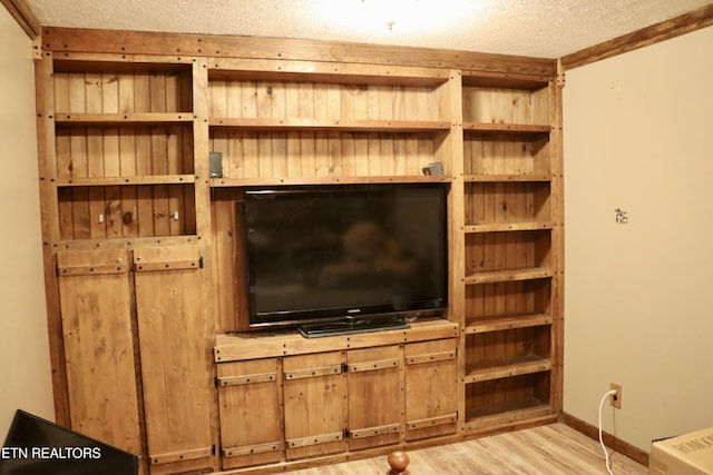 interior space with a textured ceiling, baseboards, and wood finished floors